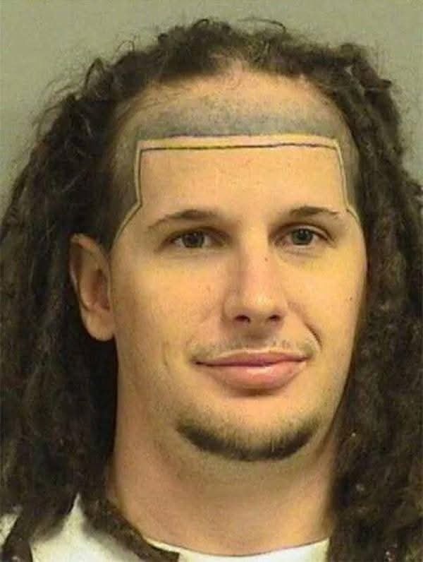 Osoba s dredmi a nezvyčajnou líniou vlasov, usmievajúca sa na kameru.