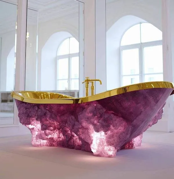 Luxusná vaňa z fialového kremeňa so zlatými detailmi v elegantnej miestnosti s veľkými oknami.