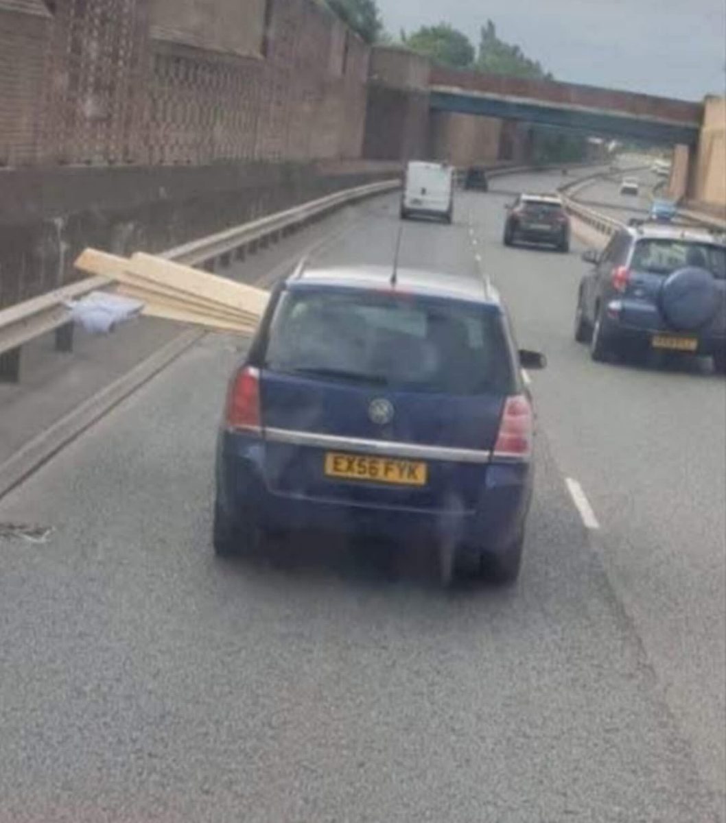 Auto s drevenými doskami trčiacimi z okna na diaľnici. Nepoistený náklad pri rýchlej jazde.