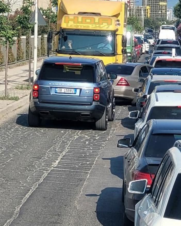 Zápcha s nákladným autom a autami na úzkej ceste v meste za slnečného dňa.