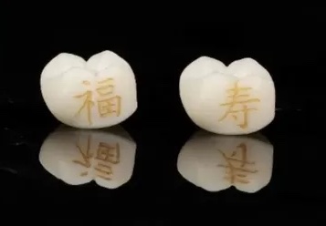 Dve zubné protézy s vyrytými čínskymi znakmi na čiernom pozadí.