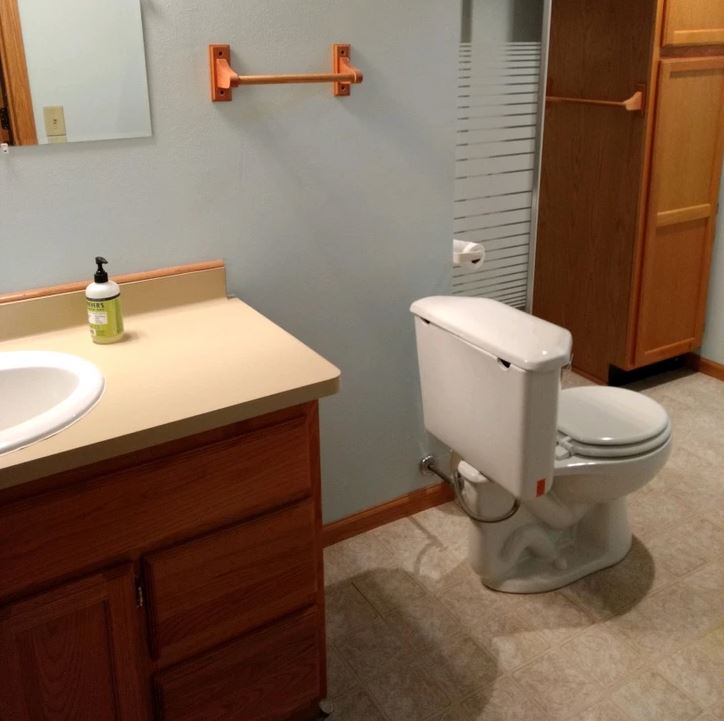 Kúpeľňa s umývadlom, toaletou a drevenými skrinkami na úložný priestor.