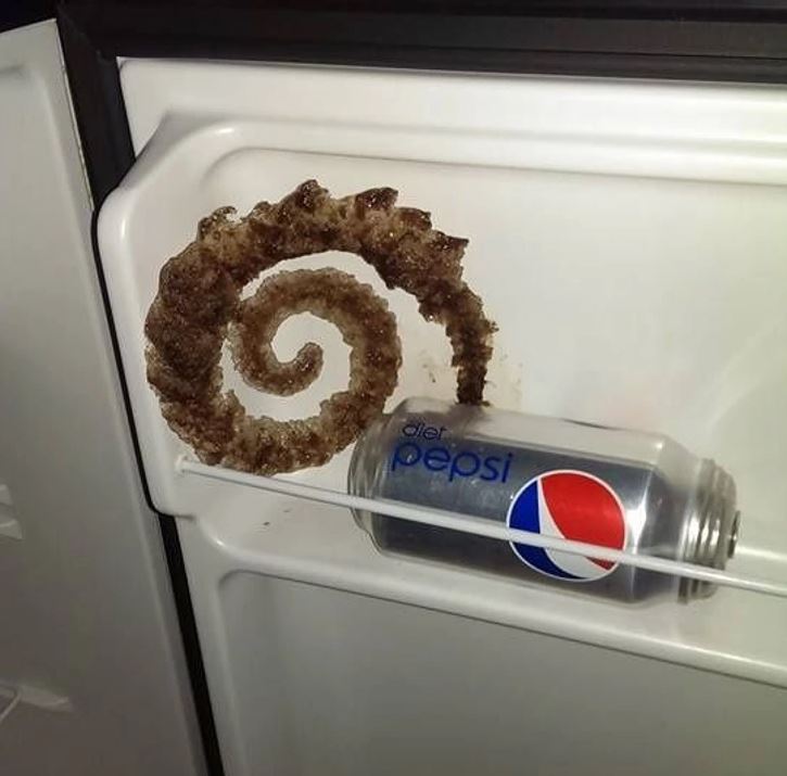 Puknutá plechovka diétnej Pepsi v mrazničke vytvára zmrznutú špirálu na dverách.