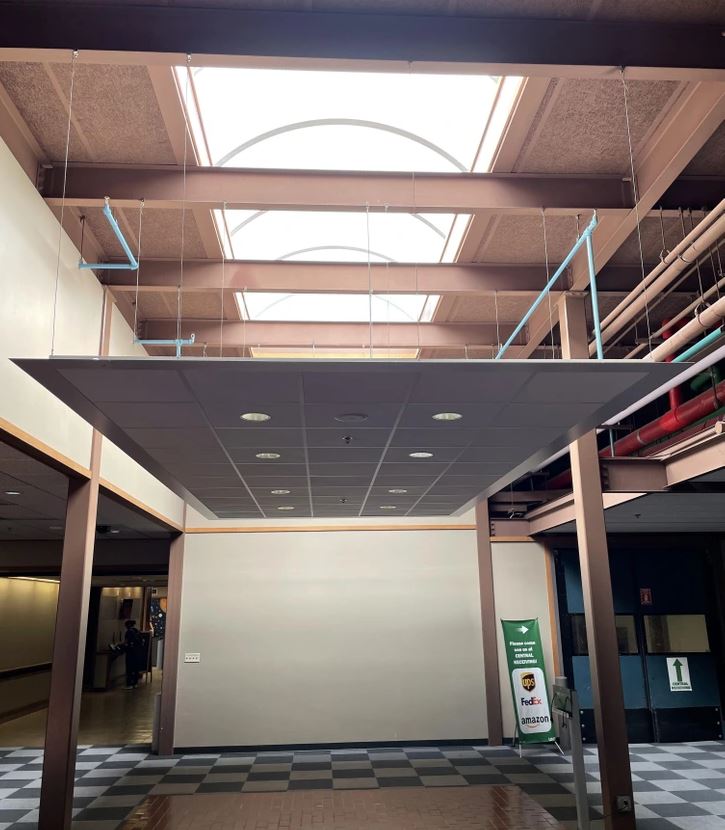 Moderná architektúra interiéru budovy so svetlíkom a geometrickými prvkami na strope.