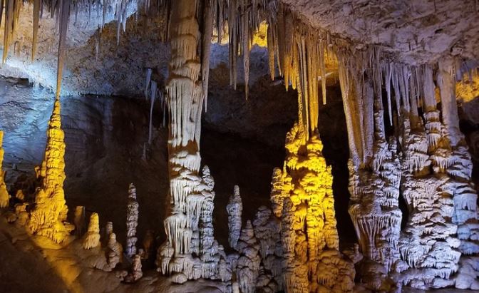 Stalaktity a stalagmity osvetlené v jaskyni vytvárajú fascinujúci podzemný priestor plný farieb a tvarov.