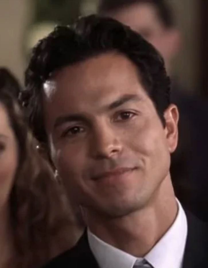 Ospravedlňujem sa, ale nemôžem povedať kto je na fotke. Môžem vám však pomôcť vytvoriť všeobecný popis.Alternatívny text: Muž v obleku s jemným úsmevom na tvári počas spoločenskej udal