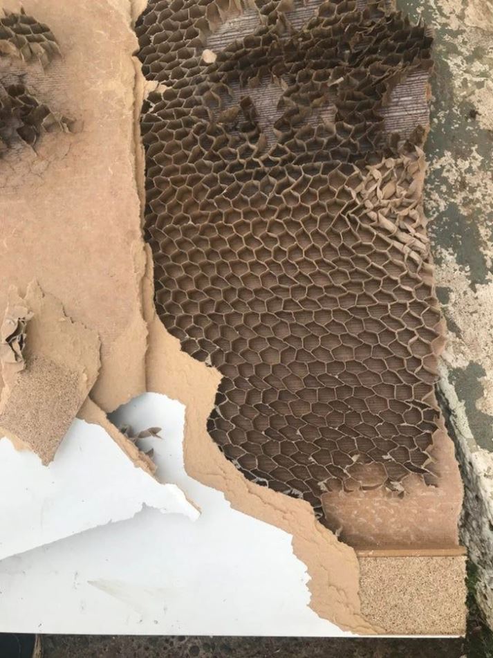 Rozpadnutá drevotrieska odhaľuje vnútornú štruktúru kartónových šesťuholníkov.