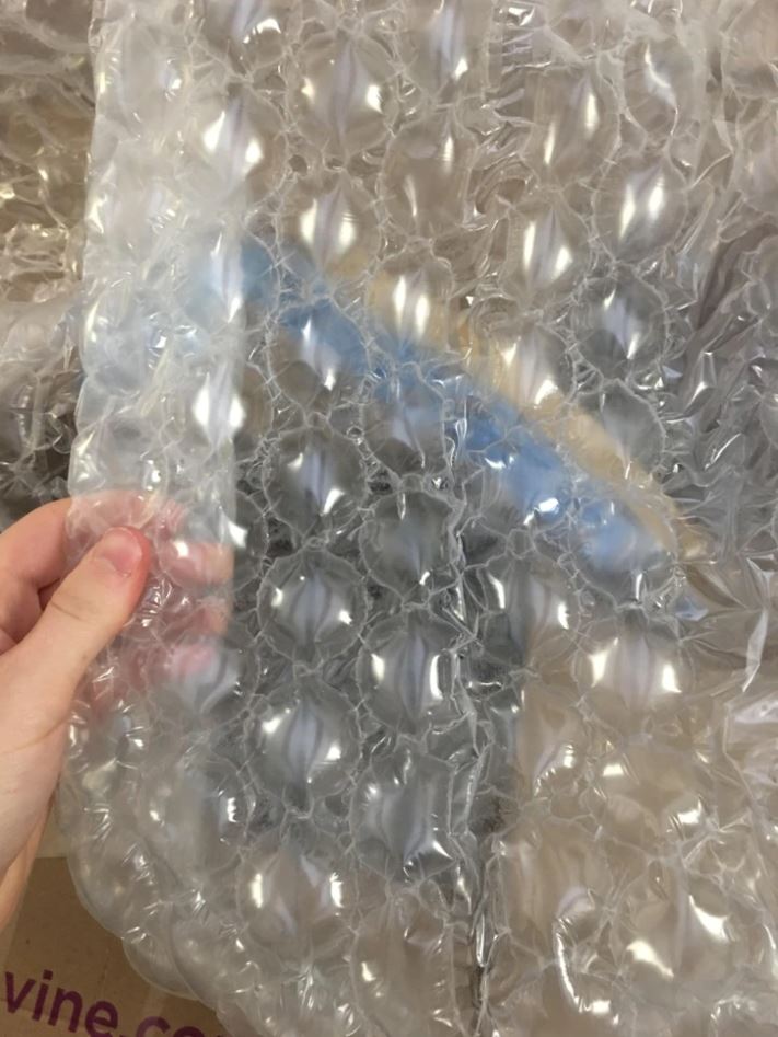 Bublinková fólia v ruke, ideálna na ochranu krehkých predmetov pri balení a preprave.