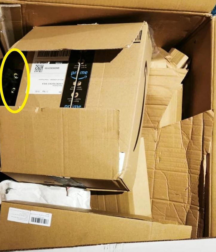 Mačka vykúkajúca z otvorenej kartónovej škatule plnej ďalších škatúľ a baliaceho materiálu.