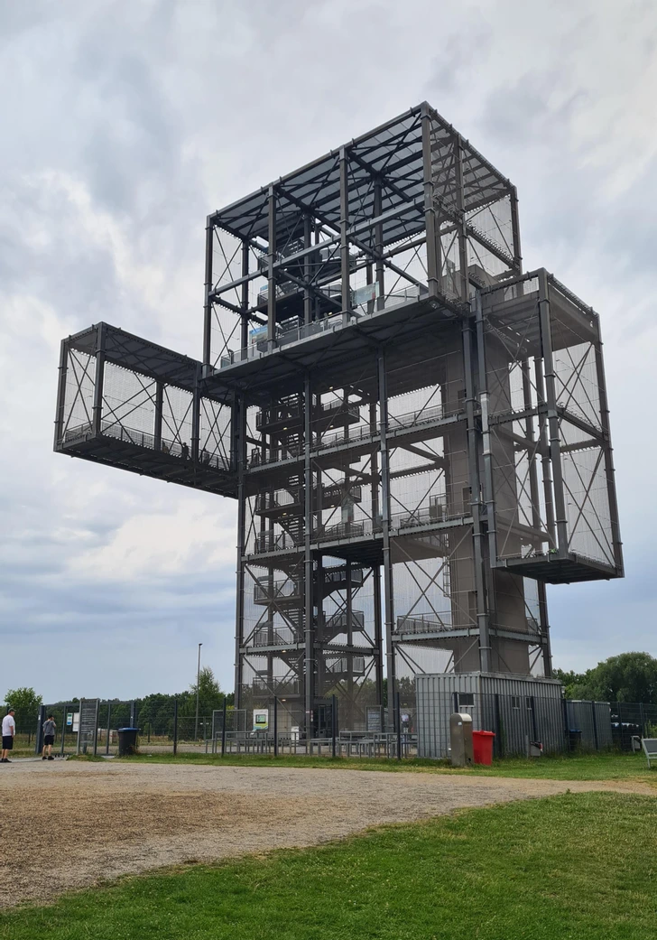 Oceľová vyhliadková veža s moderným dizajnom na pozorovanie okolitej krajiny za oblačného počasia.