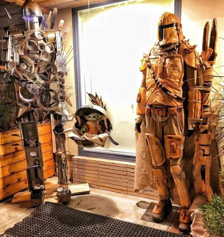 Robot z kovového odpadu, postava v brnení a zábavná figurka v kočíku pred oknom. Kreatívna inštalácia na ulici.