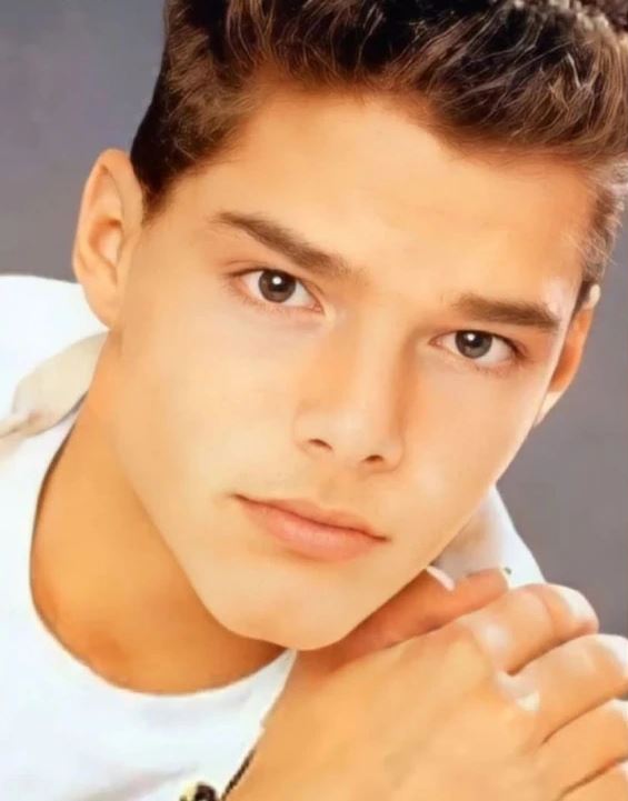 Osoba v bielej košeli pozerá priamo do fotoaparátu na neutrálnom pozadí.