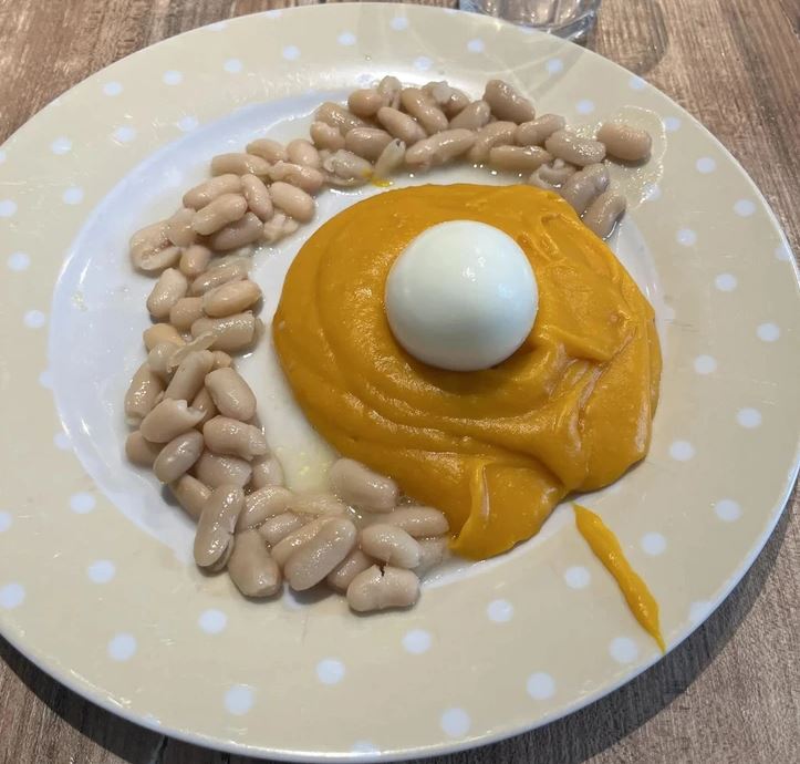 Tanier so zemiakovou kašou, vareným vajcom a bielymi fazuľkami, kreatívne servírovanie jedla.