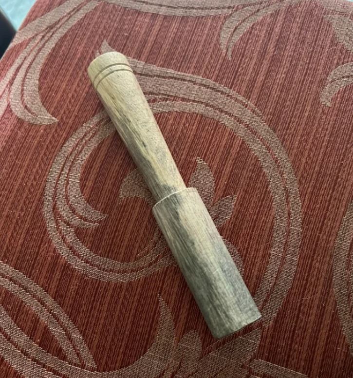 Drevená násada na textilnom podklade s ornamentálnym vzorom, detailný pohľad shora.