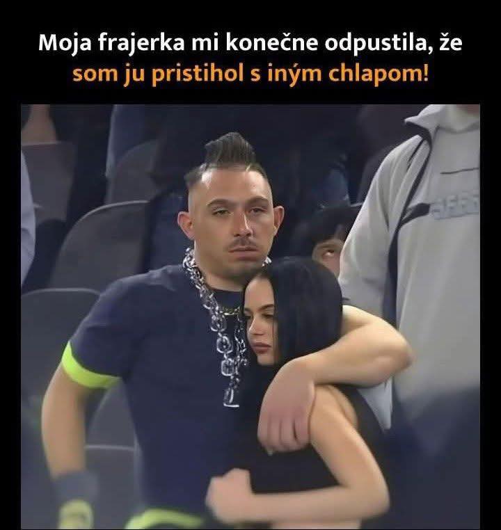 Pár objímajúci sa na verejnom podujatí; muž a žena vyjadrujú blízkosť v dave ľudí.