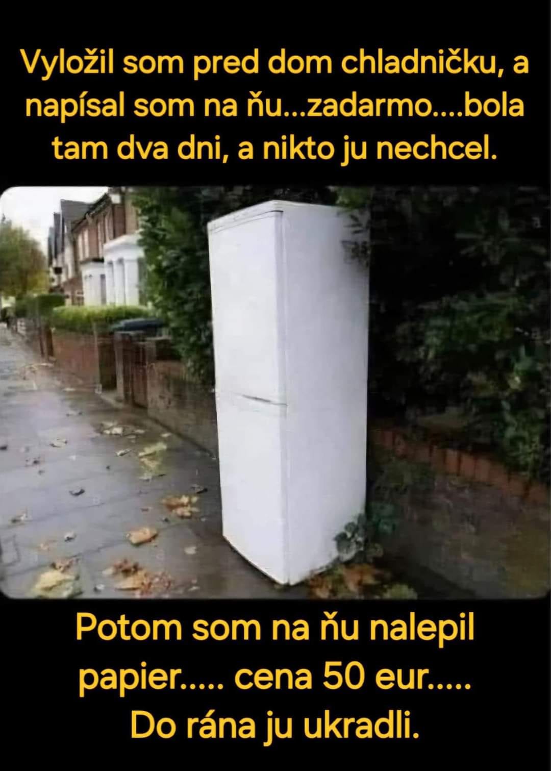 Biela chladnička stojaca na ulici vedľa plota, s vtipným textom o zmene ceny.