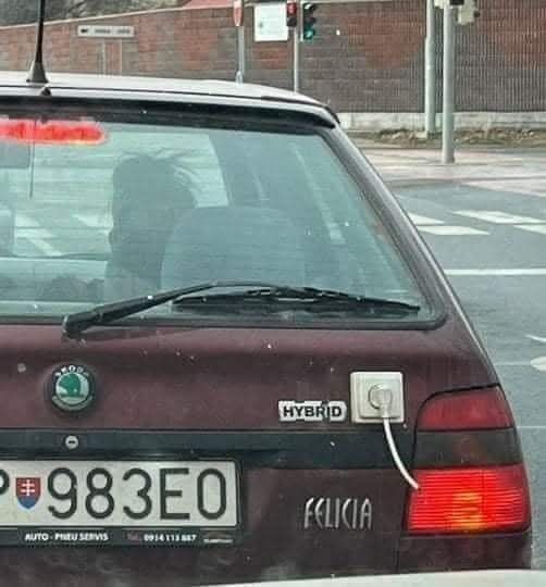 Auto Škoda Felicia s nápisom hybrid a pripevnenou elektrickou zásuvkou na zadnej časti.