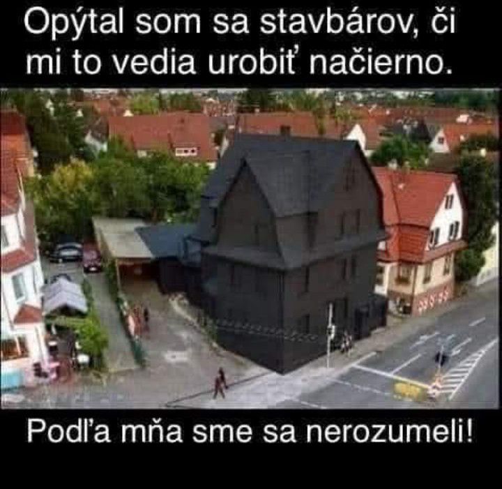 Dom natretý na čierno, vedľa tradičných domov, s humorným textom o nepochopení pri práci načierno.