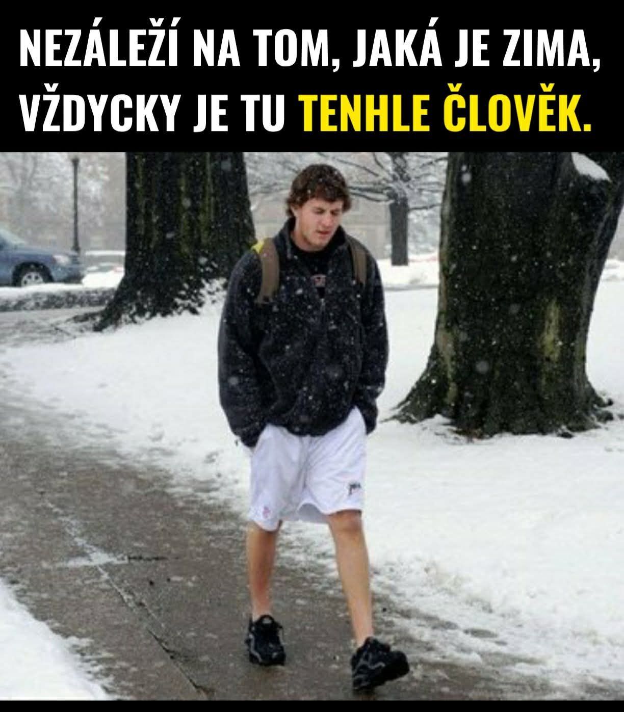 Muž v šortkách kráča zasneženým parkom.