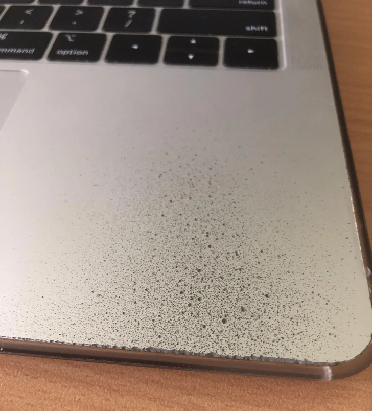 Povrch prenosného počítača so stopami opotrebenia a špinou na kovovom povrchu vedľa klávesnice.