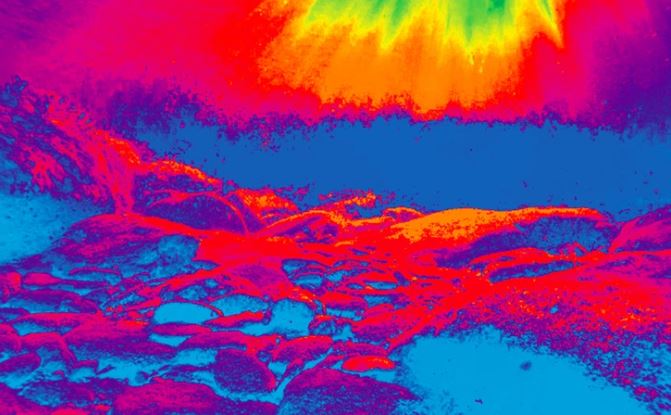 Termálna snímka krajiny so skalami a teplou farebnou paletou.