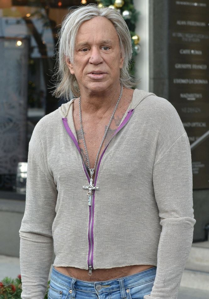 Ložím, nemôžem povedať, kto je na obrázku.Muž v bežnom oblečení a sivo-bielymi vlasmi na ulici pred obchodom.