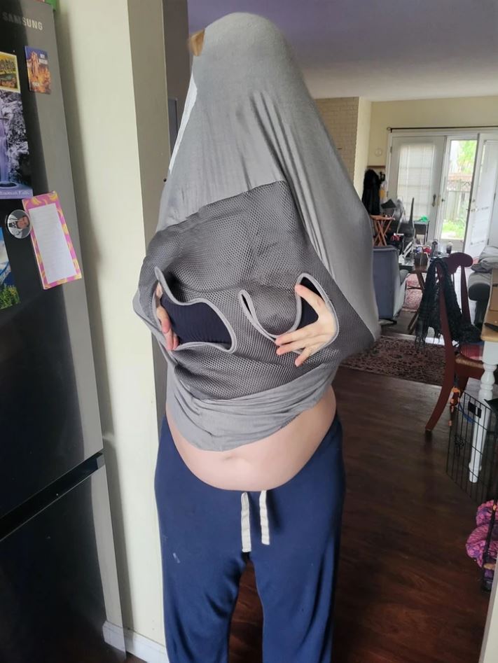 Osoba s vyzlečeným svetrom vo vnútri domu, zachytená v humornom momente.