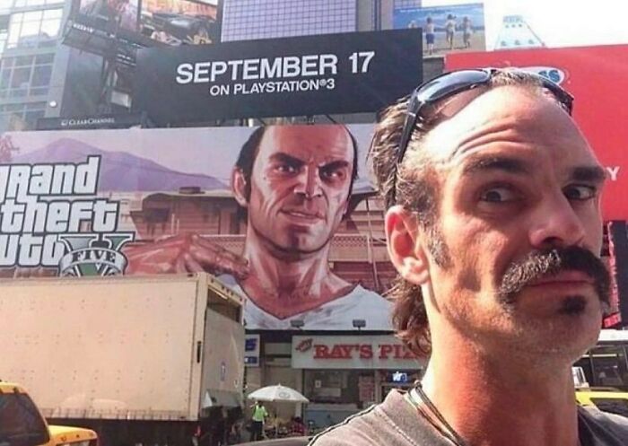 Osoba pred billboardom hry Grand Theft Auto V s oznámením o vydaní na PlayStation 3, dátum 17. september.