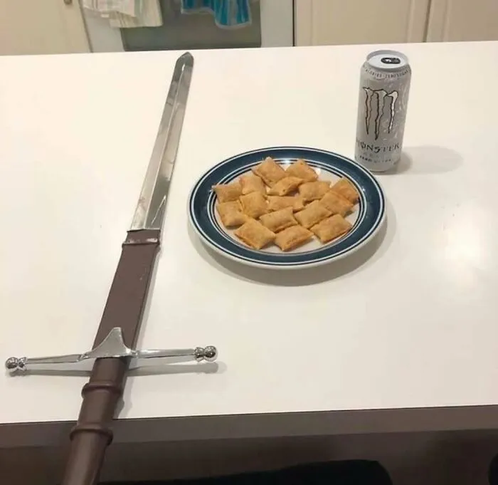 Meč leží na stole vedľa taniera s občerstvením a plechovky energetického nápoja.