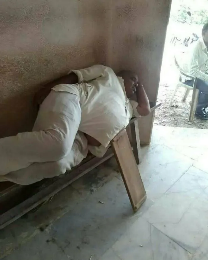 Muž leží na úzkej lavičke pri stene, odpočíva počas dňa.