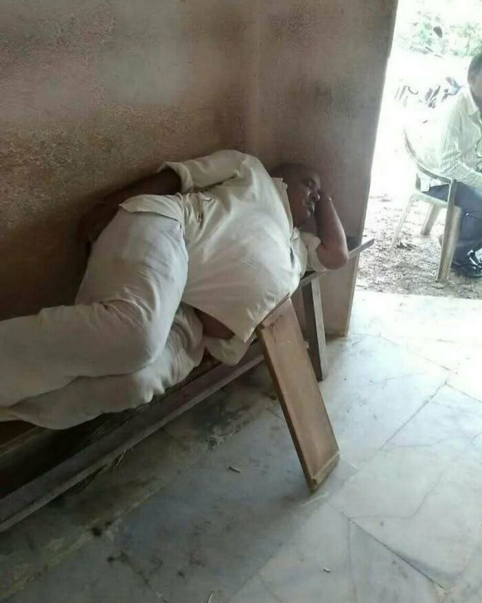 Muž v bielom oblečení leží na úzkej lavici vo vnútri miestnosti, zjavne oddychuje alebo spí.