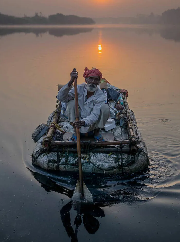 Maják na plti s pádlem, západ slnka, pokojné vody, tradičný rybolov.