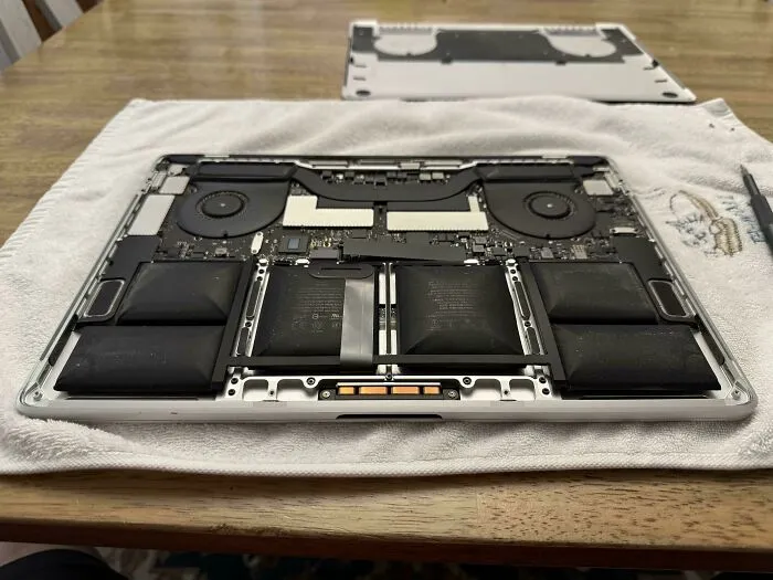 Otvorený notebook na stole ukazuje vnútornú štruktúru s ventilátormi a batériami.