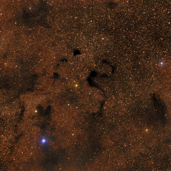 Hmlovina plná hviezd na tmavej oblohe s výraznými prachovými oblasťami v súhvezdí Štít.