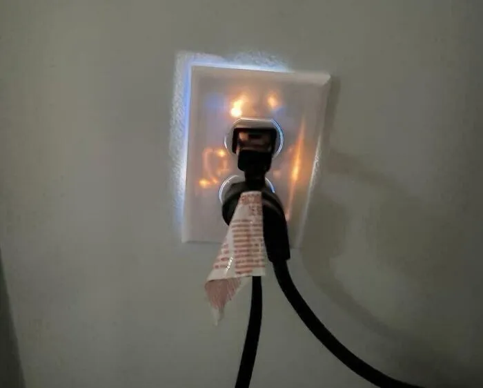 Zástrčka v elektrickej zásuvke so svetlom na pozadí, označená bielym štítkom alebo páskou.