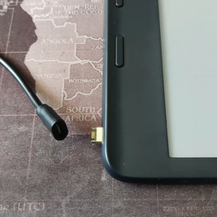 USB konektor na boku čítačky kníh vedľa káblového konektora, položené na mape Afriky.