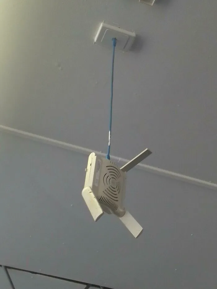 Wi-Fi router visí zo stropu pomocou modrého kábla.