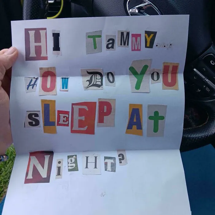 Osoba drží list s tajomným odkazom z písmen časopisu na volante auta.