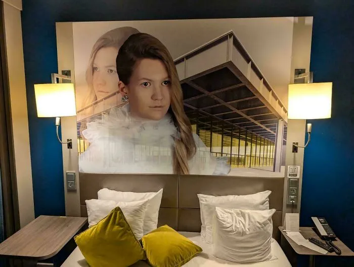 Hotelová izba s moderným umením nad posteľou, interiér s osvetlením a vankúšmi.