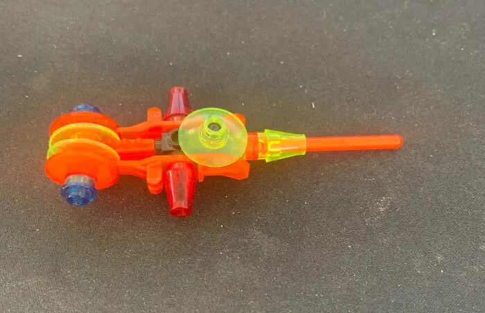 Farebný plastový komponent na čiernom pozadí, varianta hračky s neónovými prvkami.