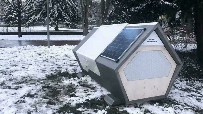 Mobilný príbytok na zimu s solárnym panelom na zasneženej lúke, vhodný pre núdzové situácie.