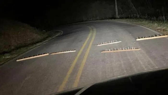 Nočné cesta so želiezom s hrotmi na asfalte. Potenciálne nebezpečenstvo pre vozidlá v tme.