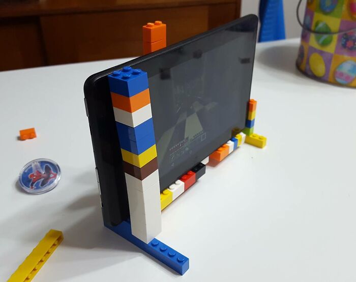 Tablet opretý o stojan z LEGO kociek na bielom stole.