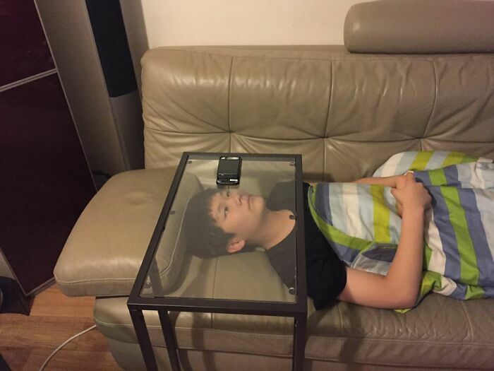 Chlapec leží na gauči s telefónom na sklenenom stolíku nad hlavou, prikrytý farebnou dekou.