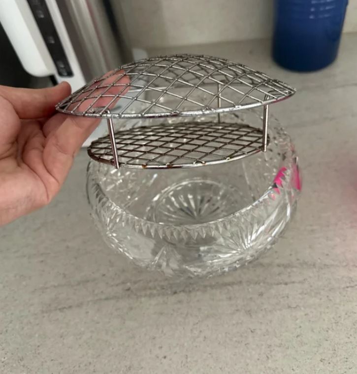 Sklenená miska s kovovou mriežkou, vhodná na chladenie či servírovanie, položená na kuchynskej linke.