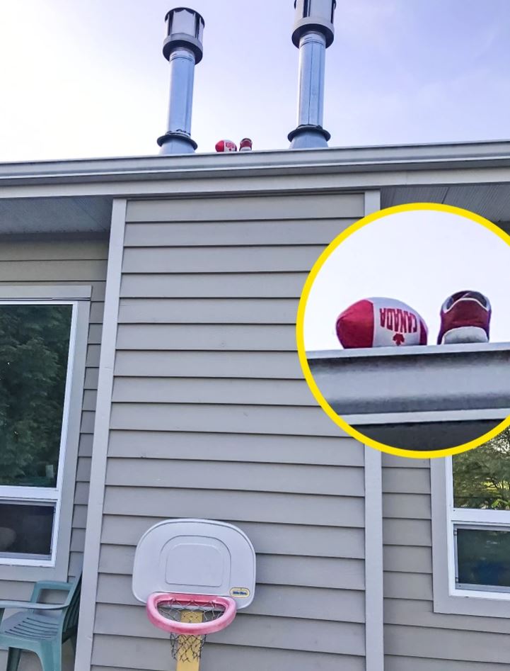 Čiapka s nápisom Canada leží na streche pri komínoch, vedľa basketbalového koša na stene domu.