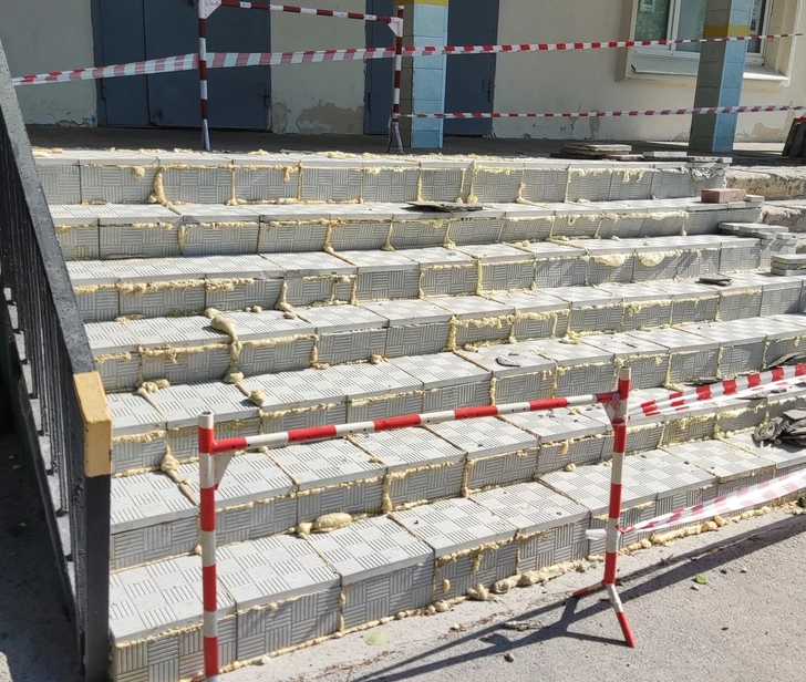 Renovácia schodov s penovou výplňou a bezpečnostnými páskami, prístup obmedzený.