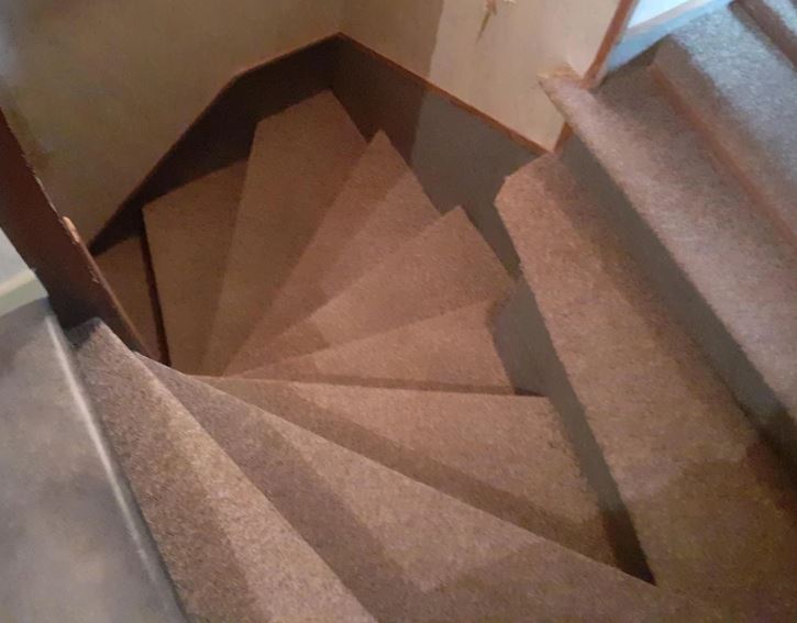 Špirálové schodisko pokryté kobercom vedúce nadol, pohľad zhora.