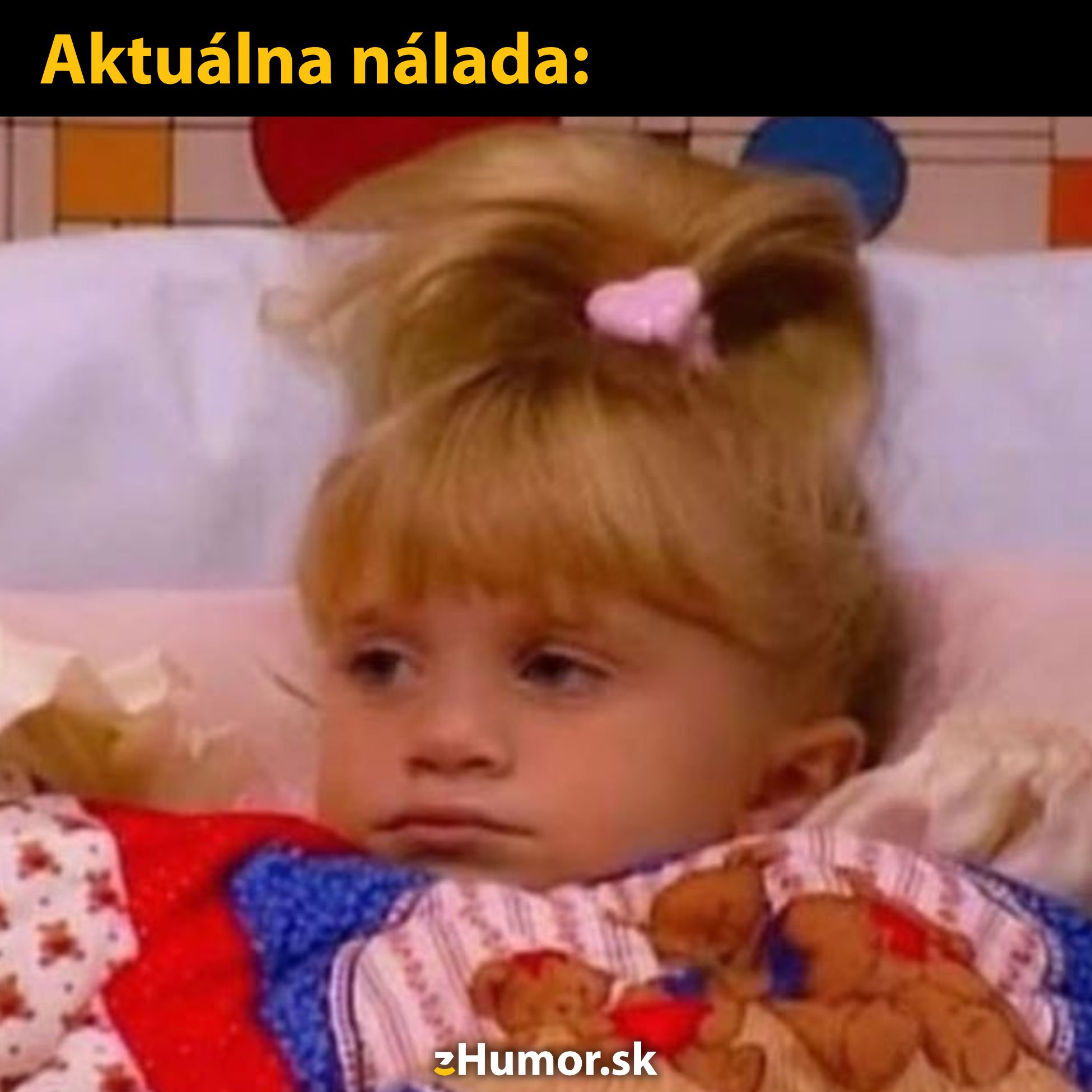 Dítě v posteli so zamračeným výrazom a veselým perinovým vzorom. Aktuálna nálada: Nie práve najlepšia.