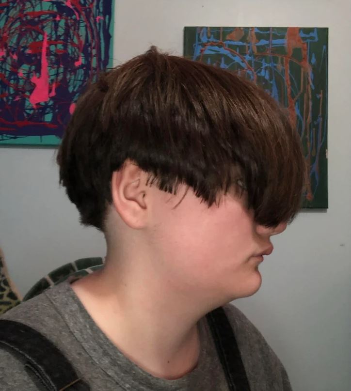 Účes bob z profilu s tmavými vlasmi v galérii moderného umenia.